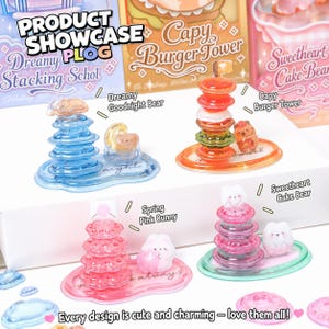Könnte beinhalten: Produktpräsentation mit Miniatur-Stapeltürmen. Die Spielzeuge umfassen ein blaues "Dreamy Stacking Schol" mit einem Bären, einen orangefarbenen "Capy Burger Tower" mit einem Bären und einen rosa "Sweetheart Cake Bear" mit einem Hasen. Der Text "Every design is cute and charming - love them all!" steht unten.
