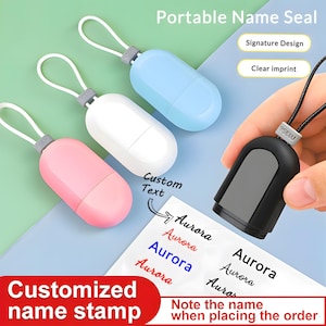 May include: A selection of portable name seals in pastel colours, with a black seal stamping the name "Aurora" onto paper. The image includes the text "Customized name stamp" and "Portable Name Seal".