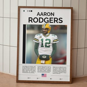 May include: A framed poster featuring Aaron Rodgers in a Green Bay Packers uniform. The poster has a white background with black text and a photo of Rodgers. The poster includes the number 12 and the American flag.