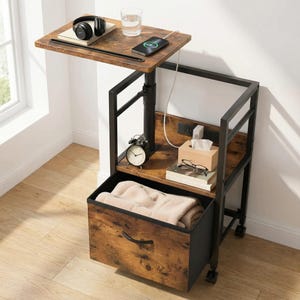 May include: A brown and black bedside table with a pull-out drawer, a shelf, and a small table. The small table has a phone, headphones, and a glass of water. The shelf has a clock, tissues, and glasses. The drawer is open and contains a folded blanket.