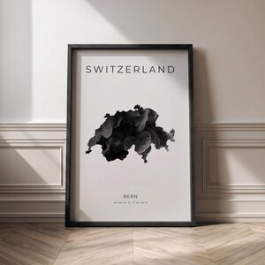 Puede incluir: Impresión enmarcada con la palabra "SWITZERLAND" en la parte superior. Debajo, una representación abstracta en blanco y negro de la forma de Suiza. La palabra "BERN" y las coordenadas están en la parte inferior. El marco es negro.