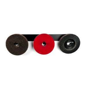 May include: Three abrasive discs in brown, red, and black are mounted on a black metal bar. Each disc has a central hole. The discs are arranged horizontally against a white background. The discs are used for sanding and grinding.