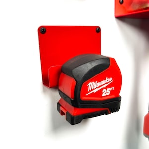 May include: Red metal wall mount with a black and red Milwaukee 25 ft tape measure attached.