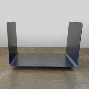Op de afbeelding: Een zwart metalen rek met een rechthoekige vorm en een plat bovenoppervlak. Het rek is gemaakt van &eacute;&eacute;n stuk metaal dat in een U-vorm is gebogen.