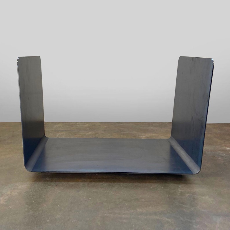Op de afbeelding: Een zwart metalen rek met een rechthoekige vorm en een plat bovenoppervlak. Het rek is gemaakt van &eacute;&eacute;n stuk metaal dat in een U-vorm is gebogen.