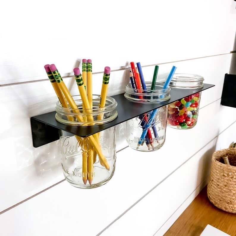 Wall Mounted mason jar shelf filled with art supplies.