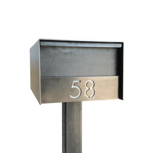 May include: A silver metal mailbox with a black metal post. The mailbox has a number "58" on the front.