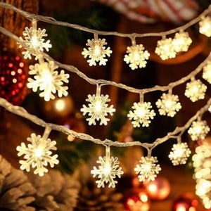 以下が含まれることがあります： 雪の結晶の形をしたLEDライトのストリング。温かみのある白色光を発します。透明なワイヤーに繋がれており、クリスマスや冬のデコレーションに最適です。