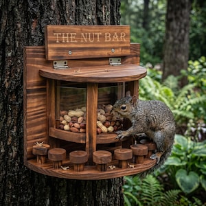 May include: A wooden squirrel feeder with the text "THE NUT BAR" engraved on a sign. The feeder is filled with peanuts and has small wooden perches. A gray squirrel is perched on the feeder, eating.