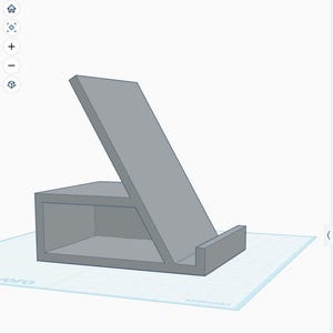 Può includere: Un supporto grigio per telefono con base rettangolare e supporto posteriore inclinato. Il supporto ha un piccolo labbro nella parte inferiore per tenere un telefono o un tablet. Il design è semplice e moderno.