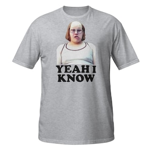 May include: A gray t-shirt featuring a graphic of a person wearing glasses and a white tank top. The text "YEAH I KNOW" is printed in bold, black letters below the image. The shirt is a short-sleeved crew neck.