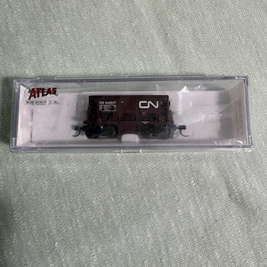 May include: A model railroad boxcar in a clear plastic case. The boxcar is brown with the letters "CN" and the number "343017" printed on the side. The case has the "ATLAS" logo.
