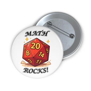 May include: A white button with a red and yellow twenty-sided die design. The text "MATH ROCKS!" is displayed below the die, with "MATH" above. The die has the numbers 3, 8, 9, 11, 14, and 20.