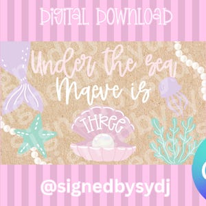 Peut inclure: Téléchargement numérique sur le thème de la mer. Le design comprend une queue de sirène, une étoile de mer et une coquille de palourde remplie de perles. Le texte dit "Under the sea Maeve is THREE". Le fond est rose avec des rayures verticales.