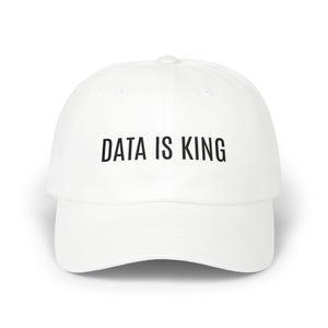 May include: White baseball cap with the text "DATA IS KING" in black block letters across the front. The cap has a curved brim and a button on top. The hat is a classic, casual style.