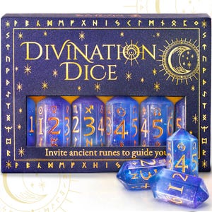Pode incluir: Um conjunto de dados de adivinha&ccedil;&atilde;o numa caixa azul marinho com letras douradas. A caixa diz "DIVINATION DICE" e "Invite ancient runes to guide you". Os dados s&atilde;o azuis com n&uacute;meros e s&iacute;mbolos dourados.