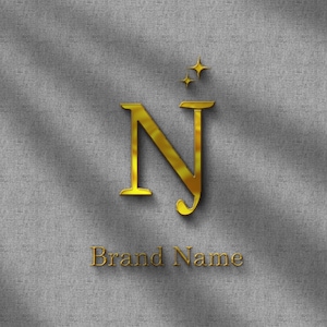 Może przedstawiać: Złote logo z literami "NJ" i dwiema małymi gwiazdkami nad nimi. Poniżej słowa "Brand Name". Logo umieszczone jest na teksturowanym, szarym tle z cieniami.