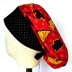 May include: A scrub cap featuring a red fabric crown with a repeating pattern of yellow and black shapes containing the text GO TAYLOR BOYFRIEND and the number 87. The front band is black with a repeating pattern of small gold dots.