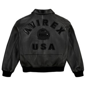May include: Black leather jacket with the word "AVIREX" arched across the upper back, above a circular emblem and the word "USA". The jacket has a ribbed hem and cuffs, and a classic collar.