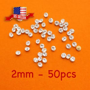 May include: Scattered clear rhinestones on an orange background. The rhinestones are 2mm in size, with a total of 50 pieces. A banner with the text "US SELLER" and an American flag is in the top left corner.