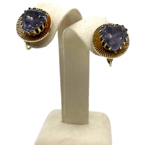 May include: A pair of gold tone clip-on earrings with a heart-shaped purple stone set in each earring.