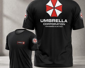 May include: Black t-shirts with the Umbrella Corporation logo. The logo is a red and white umbrella design. The text "UMBRELLA CORPORATION OUR BUSINESS IS LIFE ITSELF" is printed on the back of the shirt. A smaller logo is on the left sleeve and chest.