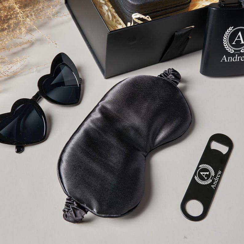 Peut inclure: Un coffret cadeau noir comprenant des lunettes de soleil en forme de c&oelig;ur, un masque de sommeil en satin, un ouvre-bouteille et une flasque. La flasque et l'ouvre-bouteille sont personnalis&eacute;s avec la lettre "A" et le nom "Andrew".