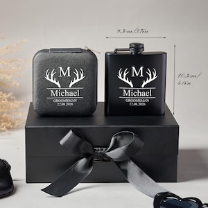 Peut inclure: Un coffret cadeau noir comprenant une flasque et un petit &eacute;tui, tous deux orn&eacute;s d'un motif de bois de cerf blanc et du nom "Michael". La flasque mesure 9,3 cm de large et 10,3 cm de haut. L'ensemble est pr&eacute;sent&eacute; dans une bo&icirc;te noire avec un ruban de satin.
