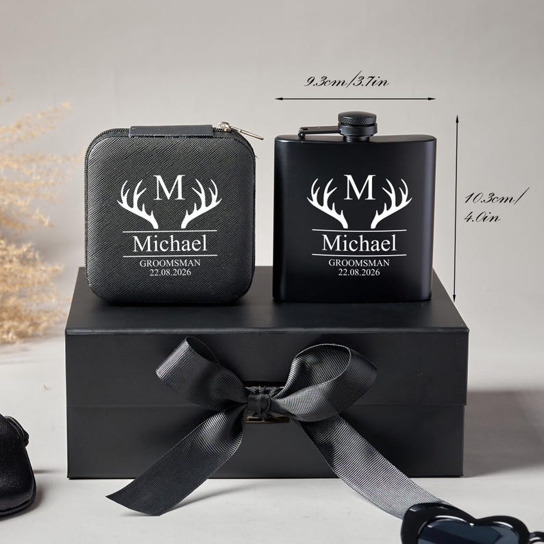 Peut inclure: Un coffret cadeau noir comprenant une flasque et un petit &eacute;tui, tous deux orn&eacute;s d'un motif de bois de cerf blanc et du nom "Michael". La flasque mesure 9,3 cm de large et 10,3 cm de haut. L'ensemble est pr&eacute;sent&eacute; dans une bo&icirc;te noire avec un ruban de satin.