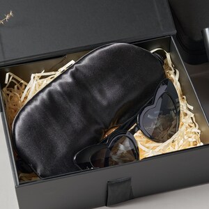 Peut inclure: Un coffret cadeau noir contenant un masque de sommeil en satin noir et des lunettes de soleil en forme de c&oelig;ur. Les lunettes ont une monture noire et des verres fonc&eacute;s. La bo&icirc;te est garnie de papier d&eacute;chiquet&eacute;.