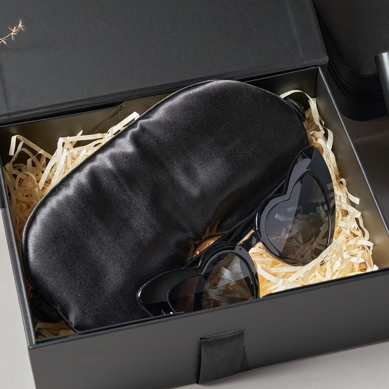 Peut inclure: Un coffret cadeau noir contenant un masque de sommeil en satin noir et des lunettes de soleil en forme de c&oelig;ur. Les lunettes ont une monture noire et des verres fonc&eacute;s. La bo&icirc;te est garnie de papier d&eacute;chiquet&eacute;.