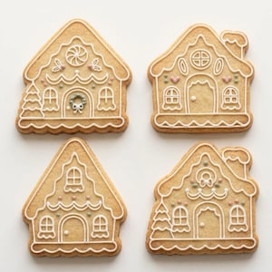 Könnte beinhalten: Vier hellbraune Lebkuchenhäuser, verziert mit weißem Zuckerguss. Jeder Keks weist unterschiedliche architektonische Details wie Fenster, Türen, Schornsteine und kleine Akzente in zartem Rosa und Grün auf, angeordnet in einem zwei-mal-zwei Raster.