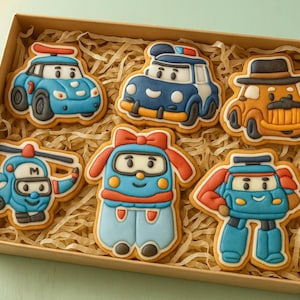 May include: A box of decorated sugar cookies shaped like cartoon vehicles and characters. The cookies are in the shape of a blue car, a police car, a yellow car with a hat, a helicopter, a character with a bow, and a robot.
