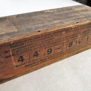 May include: A vintage wooden box with printed text and numerals. The box is a warm brown color, showing signs of age and wear. The text includes prices like 4&cent;, 9&cent;, 8 1/2&cent;, and 1 1/2&cent;. The box is likely for storing cards.