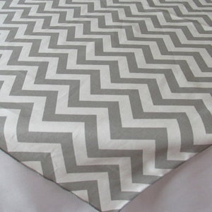 May include: A white tablecloth with a gray chevron pattern. The tablecloth is made of a soft, smooth fabric.