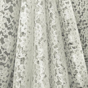 May include: White lace fabric with a delicate floral pattern. The fabric is soft and sheer, making it perfect for a variety of crafting projects.