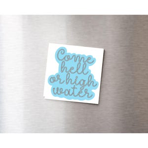 May include: A square sticker featuring the text "Come hell or high water" in a cursive font, with a rope-style outline. The text is set against a light blue background. The sticker is displayed on a metallic surface.