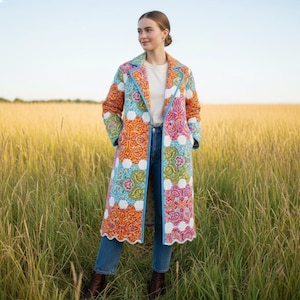 Pu&ograve; includere: Un cappotto lungo trapuntato con un colorato motivo paisley in arancione, rosa, blu e bianco. Il cappotto ha un bordo blu chiaro e un bordo smerlato. La persona indossa jeans blu e stivali marroni.