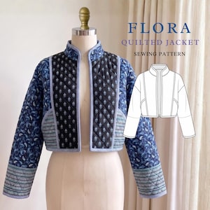 Peut inclure: Une veste courte matelassée composée de panneaux en tissu bleu à motifs cachemire et noir à motifs floraux, avec un passepoil rayé bleu clair. Le texte FLORA QUILTED JACKET SEWING PATTERN surmonte un dessin au trait blanc de la veste.