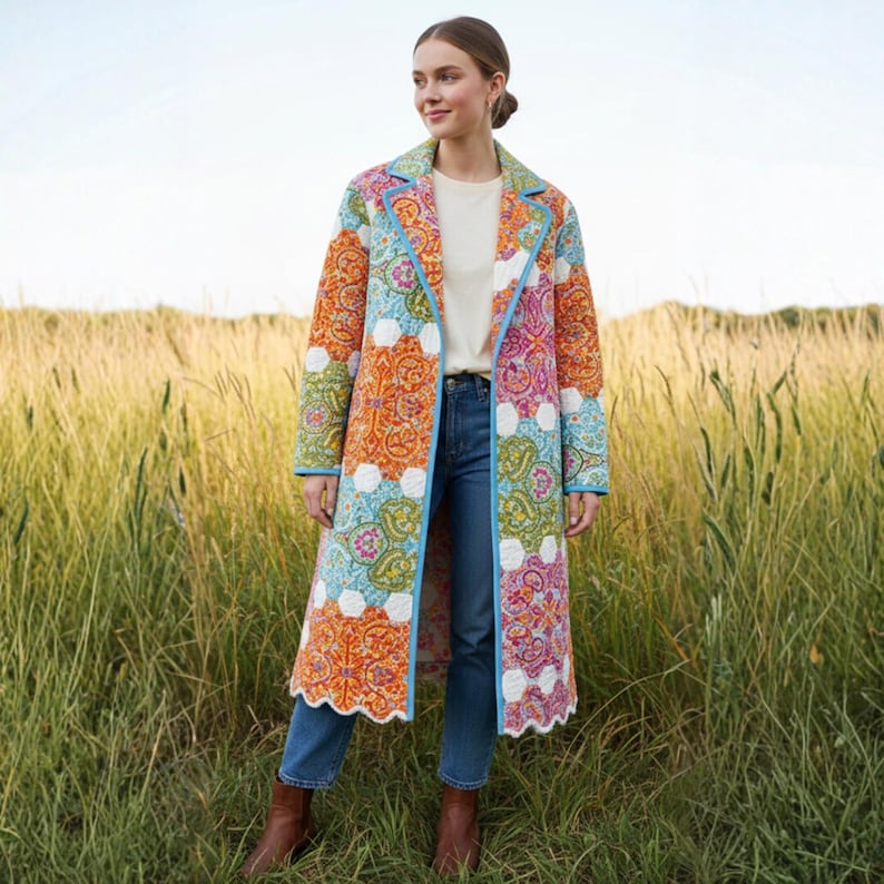 Pu&ograve; includere: Un cappotto lungo trapuntato con un colorato motivo paisley in arancione, blu, rosa e verde. Il cappotto ha un bordo azzurro e un orlo smerlato. La persona indossa jeans blu e stivali marroni.