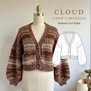 Könnte beinhalten: Ein braun-cremefarbener Strick-Crop-Cardigan mit V-Ausschnitt und Knopfverschluss. Der Cardigan hat lange, voluminöse Ärmel und wird auf einer Schaufensterpuppe präsentiert. Das Bild enthält auch eine Strichzeichnung des Cardigans und den Text "CLOUD CROP CARDIGAN SEWING PATTERN."