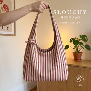 Pode incluir: Uma bolsa hobo desleixada com um padrão de listras verticais em vermelho e creme. A bolsa tem uma alça de ombro única com um pequeno detalhe de nó decorativo em um lado. O texto SLOUCHY HOBO BAG SEWING PATTERN é visível no canto superior.