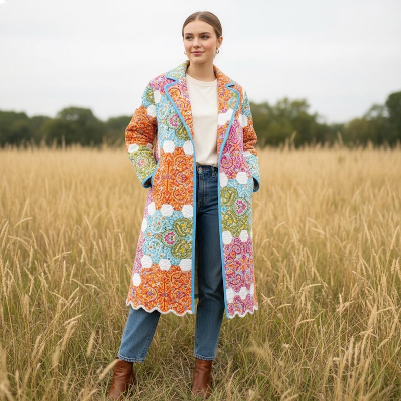 Pu&ograve; includere: Un lungo cappotto patchwork colorato con un motivo paisley nei toni dell'arancione, rosa, blu e verde. Il cappotto ha un bordo blu e un orlo smerlato. La persona indossa jeans blu e stivali marroni.