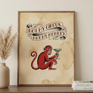May include: A framed print featuring a red monkey holding a martini glass. The monkey is illustrated in a tattoo style. The text "NOT MY CIRCUS, NOT MY MONKEY" is displayed above the monkey in a banner. The background is a stained parchment.