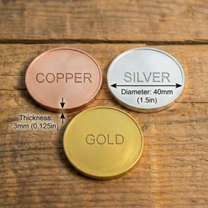 May include: Three metal coins: copper, silver, and gold. The silver coin has a diameter of 1.5 inches. The thickness of the copper coin is 0.125 inches. Each coin has its respective metal name embossed on its surface.