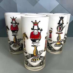 May include: A set of white glass tumblers featuring a black, red, and gold chess-themed graphic print. Each glass displays a king or queen chess piece, a knight, and a rook set against a checkered board pattern with the signature Georges Briard.