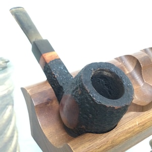 May include: A black and brown wooden pipe with a dark brown bowl and a wooden stand.