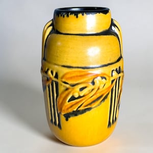 May include: A white ceramic mug with a black handle and the text "But First, Coffee" in a black, handwritten-style font. The mug is on a white surface.