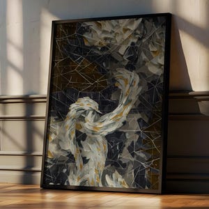 May include: Abstract art print in a black frame. The artwork features a mosaic-like design with white, gold, and dark gray elements. The framed art is leaning against a wall, with sunlight casting shadows on the wooden floor.