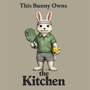 Könnte beinhalten: Illustration eines weißen Kaninchens mit grünem Poloshirt, grauen Shorts und Stirnband, das einen Pickleball-Schläger und einen gelben Pickleball hält. Der Text lautet "This Bunny Owns the Kitchen."